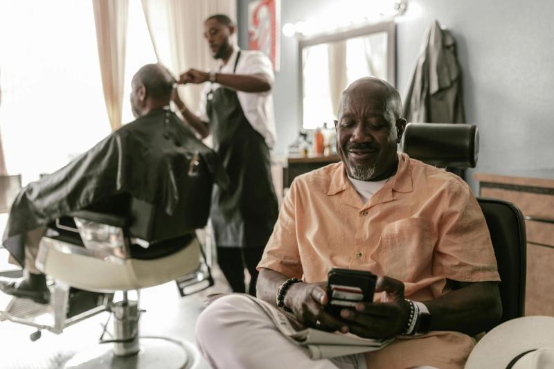 Hombre afroamericano reservando cita en la mejor aplicación de reservas de barbería
