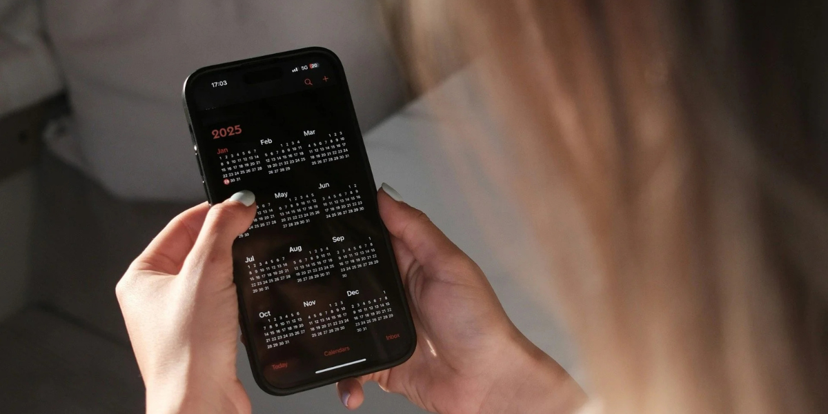 Mujer rubia con calendario en el teléfono aplicando tácticas exclusivas de programación